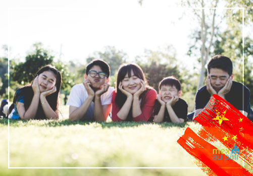 Jóvenes sonriendo recostadas en el pasto de un parque en China