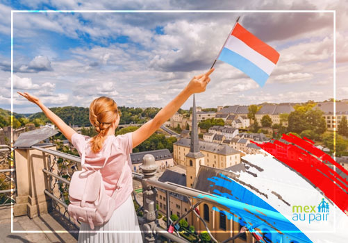 Joven con la bandera de Luxemburgo frente a la ciudad