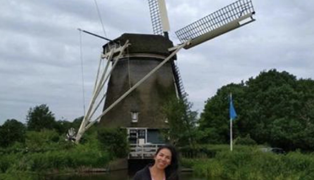 Au pair mexicana frente a un molino de viento tradicional en Países Bajos