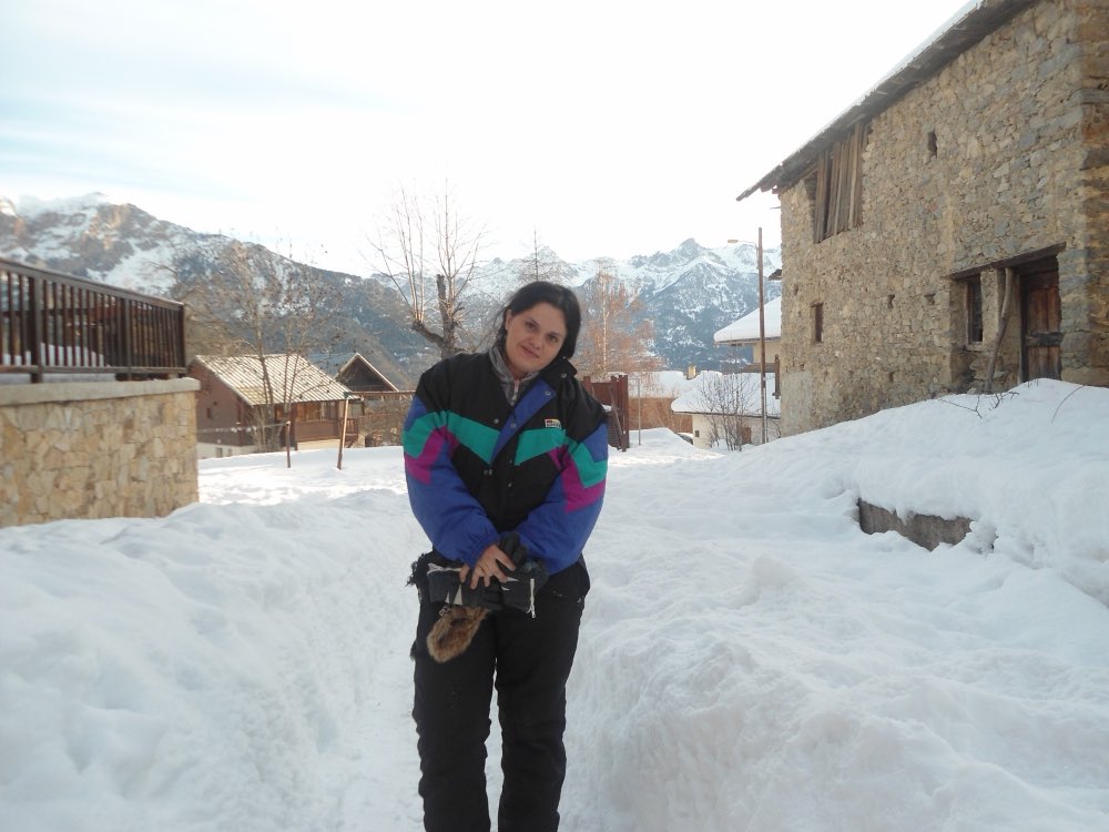 Au pair mexicana en la nieve en un pueblo de montaña con los Alpes al fondo