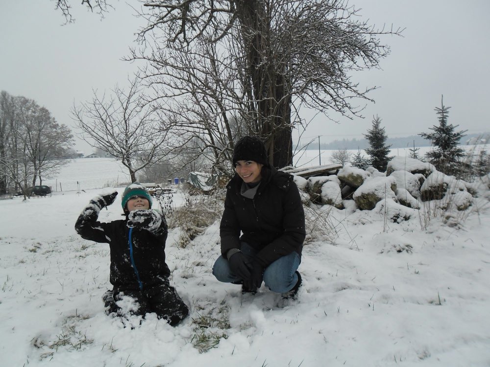 Au pair mexicana jugando en la nieve con el niño de su familia anfitriona