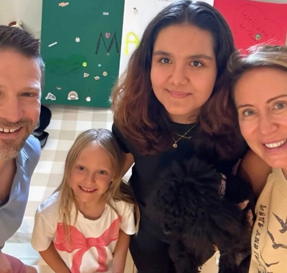 Majo con su familia anfitriona en Estados Unidos frente a un cartel de bienvenida con los colores de México